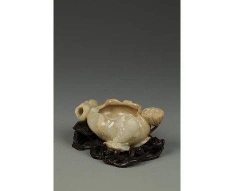 A CHINESE CELADON JADE WASHER, of lotus form, the stone partially calcified, 3.75" long; hardwood stand