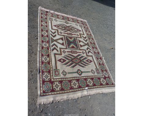 A bordered, patterned and fringed woven rug, burgundy ground border, cream central ground, green and gold burgundy Aztec/geom