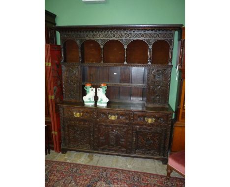 An imposing, profusely carved Oak Welsh Dresser, the enclosed base with three frieze drawers and three cupboards below, the r