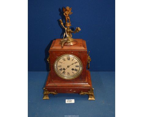 A two train movement red marble mantle Clock having Roman numerals with mask handles to the side, a key and a metal Cherub pl