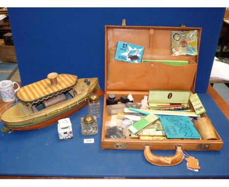 A Briefcase and contents including stationery, fountain pens, rulers, ink bottles etc. and a tin boat.