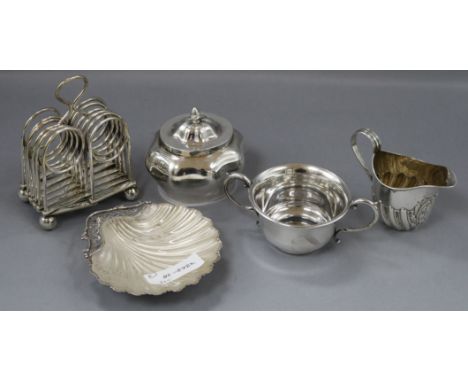 A George V silver scallop butter dish with glass liner, a serpentine oval tea caddy, a small cream jug, a sugar bowl and a pl