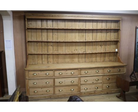 A large Victorian pine dresser, with three shelf rack and twelve long drawers, on plinth foot W.305cm H.243cm