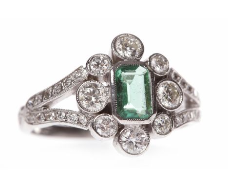 EMERALD AND DIAMOND DRESS RINGwith a central step cut emerald 5.6x3.5mm surrounded by round brilliant cut diamonds, on bifurc