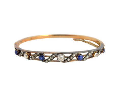 A Victorian gold and silver set, diamond and sapphire oval hinged bangle, the front in a scrolling design, mounted with three