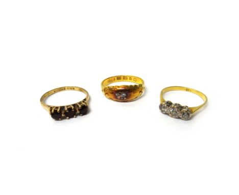 A gold and diamond three stone ring, mounted with a row of cushion shaped diamonds, a gold and diamond single stone ring and 