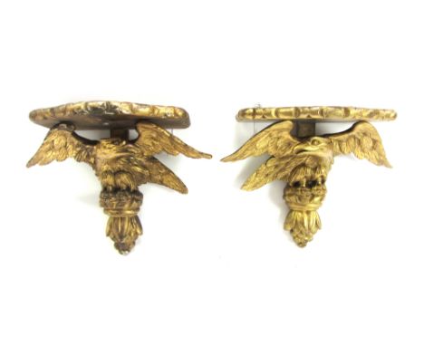 A pair of giltwood wall brackets, late 19th/early 20th century, each shaped shelf over an eagle and fruiting finial, 32cm hig