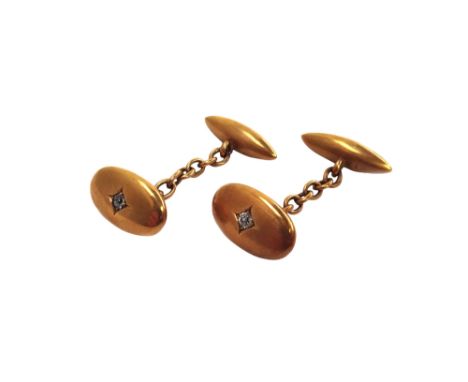 A pair of gold and diamond set cufflinks, each with an oval front, centred by a cushion shaped diamond and with a torpedo sha