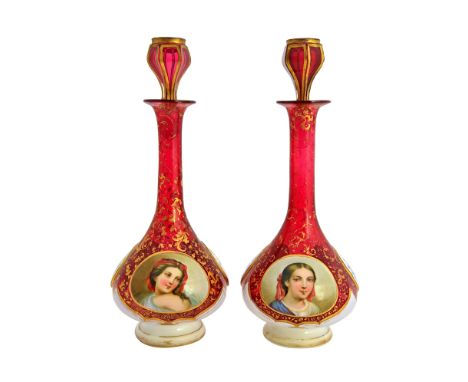 A pair of Bohemian cranberry glass and enamel overlay decanters and stoppers, 19th century, the enamel decorated with opposin