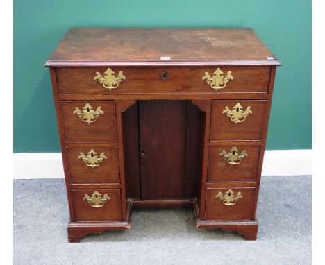 A mid-18th century mahogany kneehole writing desk, with seven drawers about the central cupboard, on bracket feet, 80cm wide.