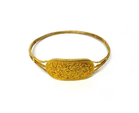 A gold circular bangle, the front curved panel decorated with blossom and floral sprays, diameter 9.3cm, weight 24.8 gms.