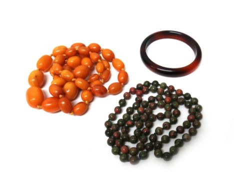 A single row necklace of graduated oval vary coloured butterscotch coloured amber beads, a stone bead necklace and a costume 