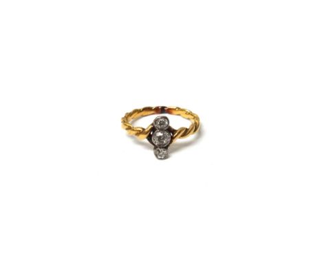 A gold and diamond set three stone ring, mounted with cushion shaped diamonds, in an over and under design, the shank of rope