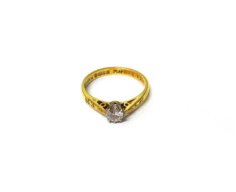 An 18ct gold and platinum, diamond set single stone ring, claw set with a circular cut diamond, between decorated shoulders, 