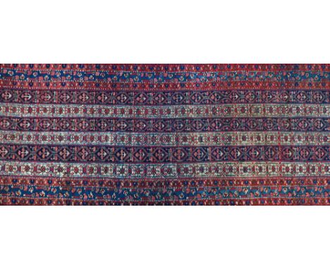 A West Persian runner, the field with six bands of connecting flower and bracket design, an indigo flower and ribbon border, 