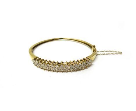 A gold and diamond set oval hinged bangle, the front mounted with rows of princess cut diamonds, on a snap clasp, with a fold