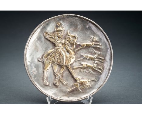 A PERSIAN PARCEL-GILT SILVER REPOUSSE 'HUNTER' DISHPersia, 17th century or earlier. The flat dish with a lipped rim, centered