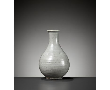 A GRAYISH-WHITE GLAZED BOTTLE VASE, JOSEON DYNASTY 朝鮮王朝灰白釉瓶Korea, 18th century or earlier. The pear-shaped body supported on 