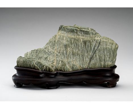 A SOAPSTONE SCHOLAR'S ROCKChina, 20th Century. The green stone horizontally orientated and outlined with mountain peaks. With