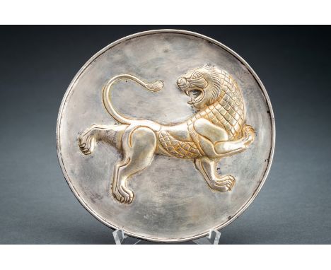 A PERSIAN PARCEL-GILT SILVER REPOUSSE 'LION' DISHPersia, 17th century or earlier. The flat dish with a lipped rim, centered b