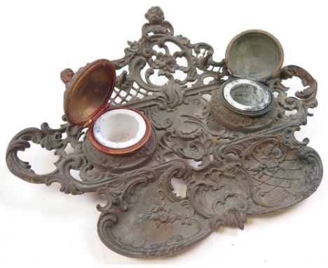 Brass desktop ink stand decorated with cupids, ceramic liners still present, 25cm x 33.5cm approx. 