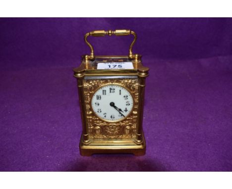 An early 20th century mantle of carriage clock having ornate ormolu and enamel worked face having double arrow mark and Franc