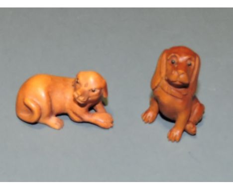 Two carved wood netsuke, in the form of dogs, one seated, one lying down, each with character marks to base, L. 4.5cm. 