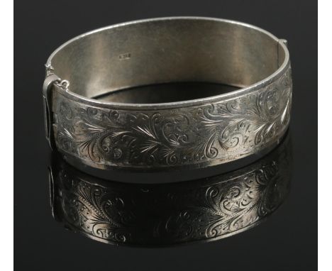 A silver hinged bangle, with embossed scrolled decoration to one side. Assayed for Birmingham, 1964, by Henry Griffith &amp; 