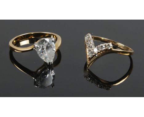 A 9ct gold and cubic zirconia wishbone ring along with a yellow metal single stone ring. Both L 1/2. 1.77g and 2.48g.  