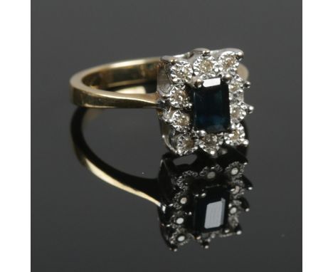 A 9ct gold sapphire and diamond ring. The square cut sapphire surrounded by a border of ten diamonds. Size N. 3.76g.  