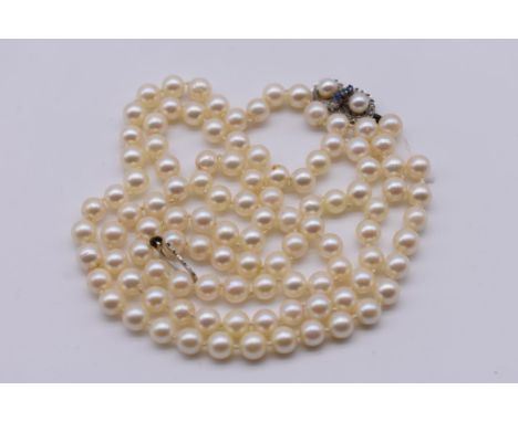 A single strand of pearls, the white gold clasp set double pearl and sapphire, stamped with import mark 750, 78cm long. 