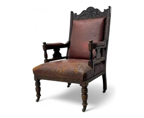 Victorian walnut framed armchair, shaped pediment carved with scrolling foliage, upholstered in leather, on ring turned front