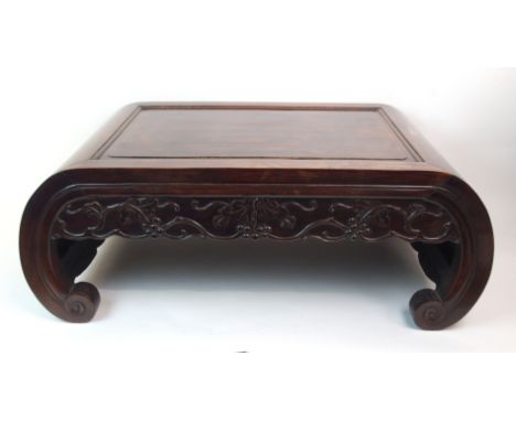 A CHINESE HARDWOOD KANG (TABLE) with carved berry and vine frieze above inswept scroll legs, 28cm high x 73cm wide x 42cm dee