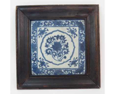 A CHINESE BLUE AND WHITE TILE painted with a central lotus roundel surrounded by foliate spandrels and scrolling border, 19.5