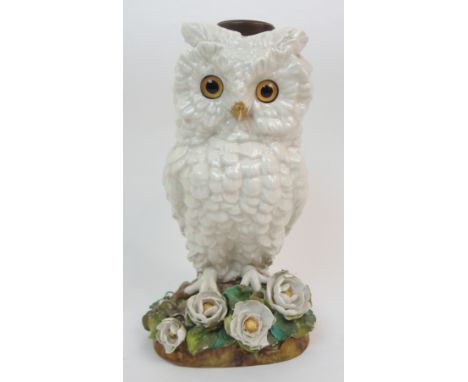 A VICTORIAN PORCELAIN OIL LAMP BASE modelled as a white owl with amber glass eyes, standing upon a naturalistic base with flo