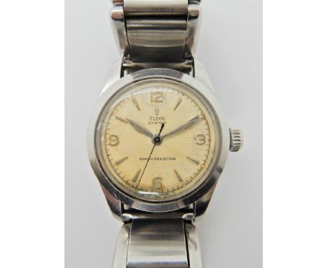 A VINTAGE TUDOR OYSTER SHOCK RESISTING WRISTWATCH in stainless steel. Cream coloured textured dial with Arabic and baton nume