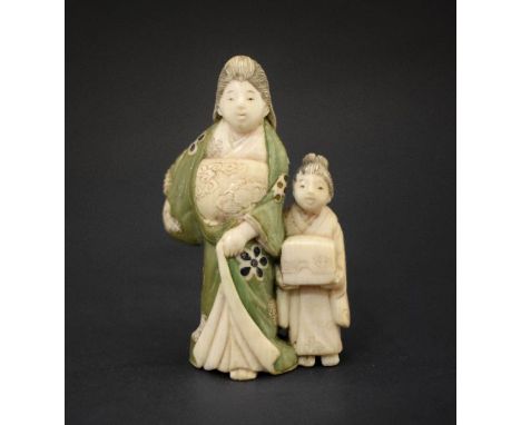 Japanese carved ivory netsuke depicting a standing woman and child, Meiji period, having green stained and metal inlaid decor