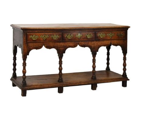 George III oak low dresser, fitted three drawers, shaped apron below, standing on six bobbin turned supports united by a plat