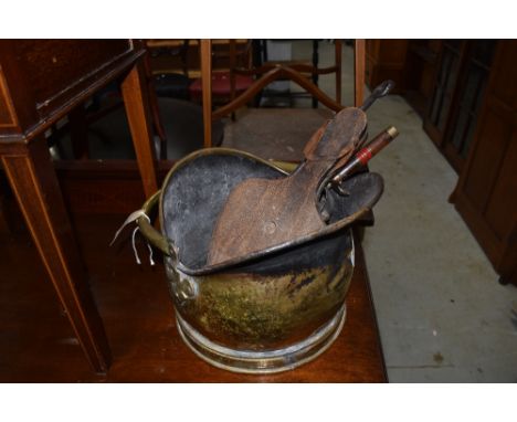 A traditional brass coal helmet and selection of fire tools, including bellows