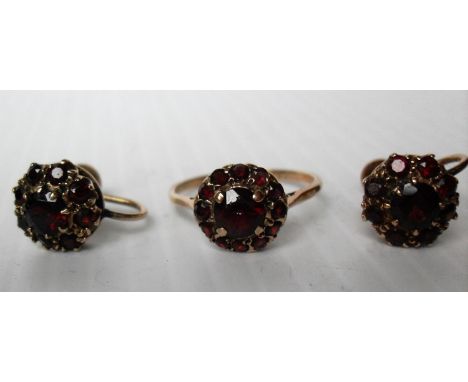 A 9ct gold ruby ring and matching earrings. The central stone surrounded by thirteen smaller rubies in a claw setting, size Q