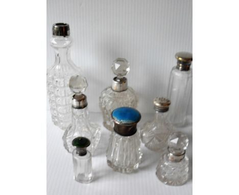 An assortment of eight cut-glass crystal  late Victorian / Edwardian silver-collared scent bottles, two with enamel tops (sli