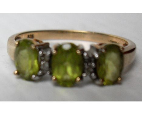 A 9ct yellow gold three-stone oval cut peridot ring, size R, in a claw setting, hallmarked for Birmingham, 2.36g 