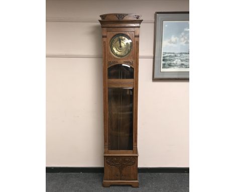 A continental oak longcase regulator clock with brass dial