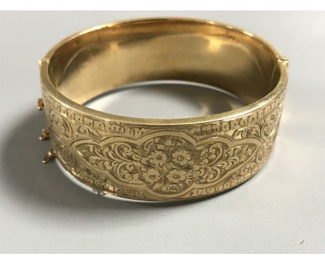 A 9ct gold bangle, 25.8g. CONDITION REPORT: Safety chain broken. Various minor dents and a small split, see close up image. 