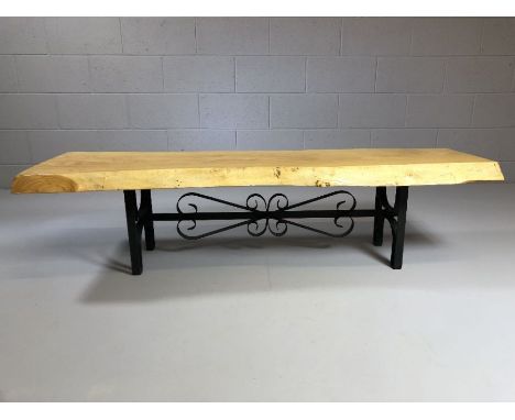 Rustic coffee table on wrought iron base with the top a section of a tree trunk