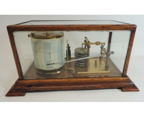 An early 20th Century barograph in oak case with bevelled glass panels and together with some Negretti & Zambra recorder char