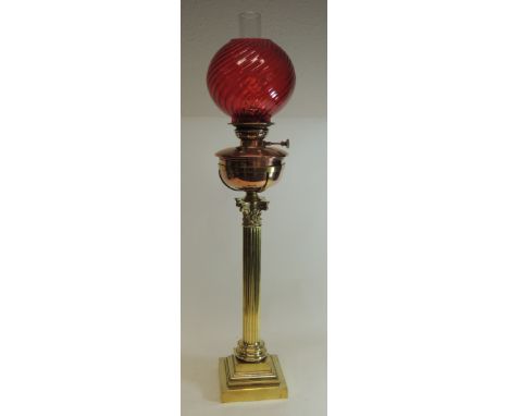 A large Victorian brass and copper oil lamp with moulded swirl pattern cranberry glass shade, copper reservoir in brass holde