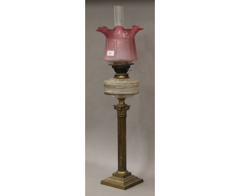 A Victorian Corinthian column oil lamp with cranberry glass shade