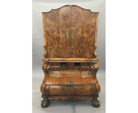 A 19th century Dutch burr walnut secretaire cabinet, the top section with twin cupboard doors with floral top carving and gil