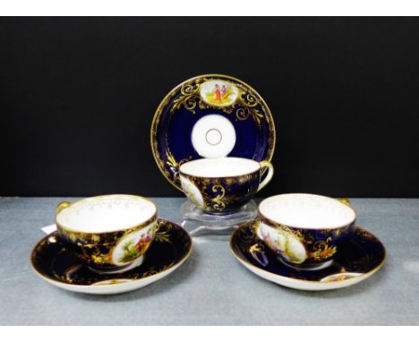 A set of three Vienna porcelain cups and saucers with male and female figural panels against a cobalt ground with gilt rims a
